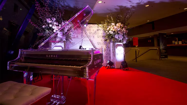 A fancy grand piano with flowers around it.