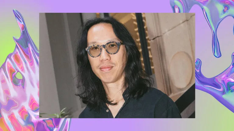 A young, Asian man with long black hair and glasses smiles subtly, wearing a dark shirt. The image overlays a background of a purple iridescent swirl, looking like water.