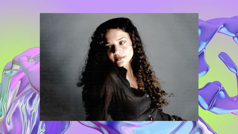 Portrait of a woman with long curly hair and a gentle smile against a grey backdrop. The image bac a background of a purple, iridescent swirl, looking like water.