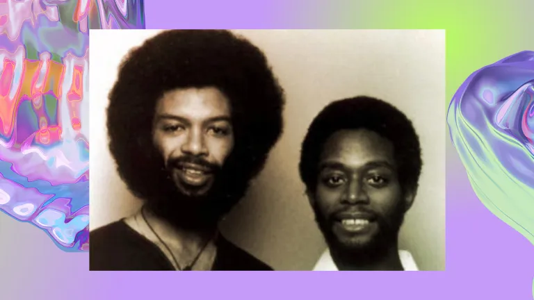Vintage photo of two black men smiling, one has a tall afro hairstyle and thick beard. The background is an iridescent purple swirl, looking like water.