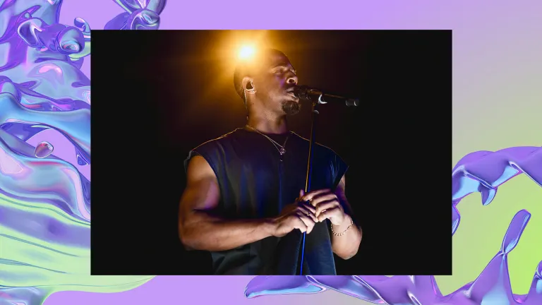 Khamari sings into a microphone lit by an overhead yellow light.