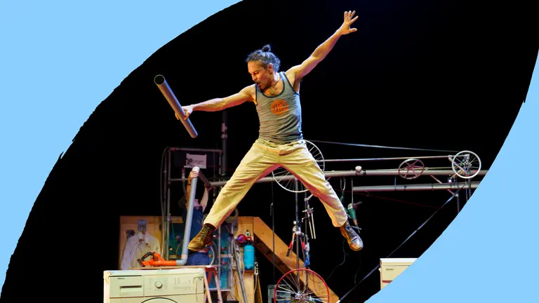 A man leaps off a washing machine with his arms out wide.