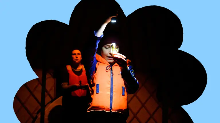 A person holds up a small toy, shining a torch on it.