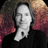 A black and white photo of Conductor Eric Whiteacre with a red and yellow sparkly background