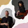Two musicians with string instruments, a man with short hair and a beard on the left, and a woman with dark hair and a smile on the right.