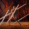 A man wearing lion skin aiming with wooden spear.