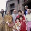 Cast members from The Royal Tenenbaums stand together outside a large house. They are all posing in a formal group portrait.