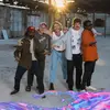 The five members of King Stingray stand with their arms around each other in an abandoned lot.