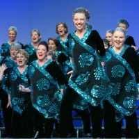 A group of people singing on stage wearing black and blue.