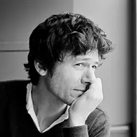 A man looks off to his left with his face resting in his hand.