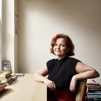 A white woman with short red hair sitting at a desk.