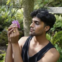 A man holds a purple flower.