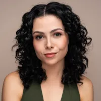 Black haired woman standing front on wearing a green sleeveless top.