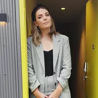 Amy Thunig an author standing in a door way wearing a suit.