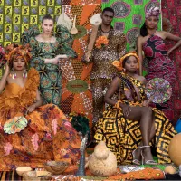 A group of people sitting or standing against a patterned fabric backdrop, wearing colourful, patterned clothing.