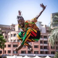 A person jumping in the air with their hands raised and legs crossed.