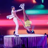 A rollerskating duo perform, the man flips the women and she is mid-air, upside down.