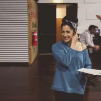 A woman in a blue top, smiling.