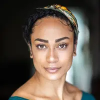 A headshot of a woman with dark features staring intently at camera