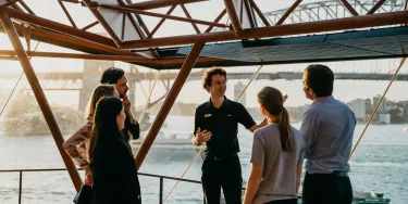 A tour guide with a group of people outside the Sydney opera house.