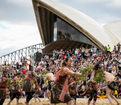 Women in sand pit performing indigenous dance in the Homeground of Sydney opera house.