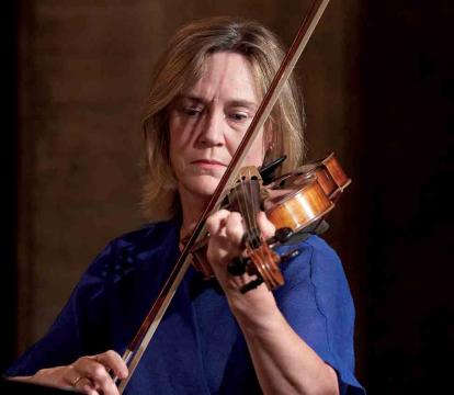 A woman in a blue top plays the violin.
