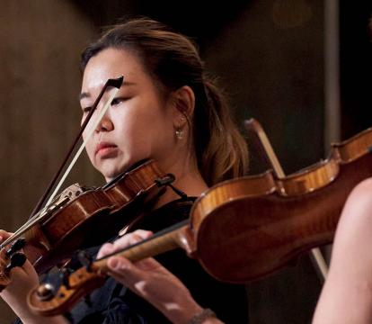 Two female violin players stand playing the violin