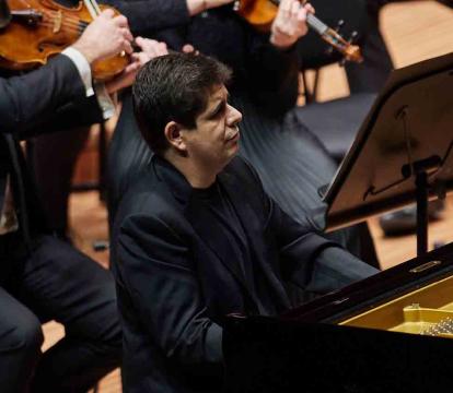 Javier Perianes in an all black suit plays the piano.