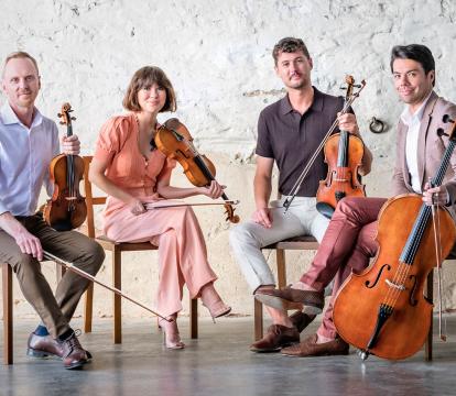 A string quartet holds their instruments looking at the camera