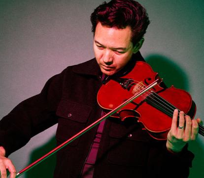 A man in black jacket playing a violin.