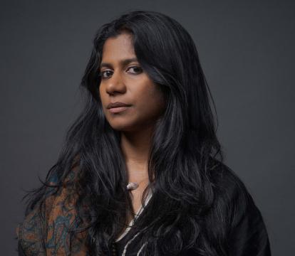 A Southern Indian woman in her 30s with long brown hair looks at the camera.