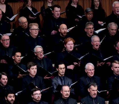 A choir singing with black folders in their hands.