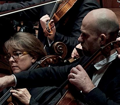 A man and a woman playing a cello in an orchestra.