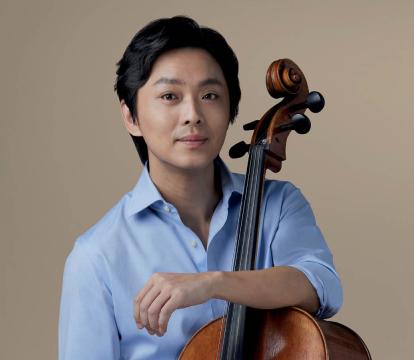 A man in a blue shirt holding a cello.