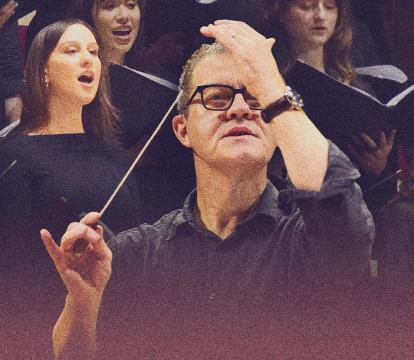 A conductor stands in front of a choir.