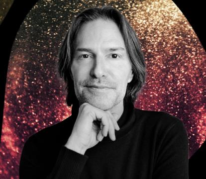 A black and white photo of Conductor Eric Whiteacre with a red and yellow sparkly background