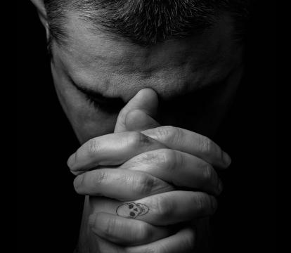 A man resting his forehead on his hands.