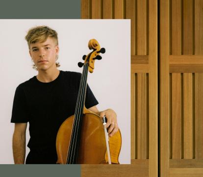 A young blonde man in black t-shirt holding a bass violin.