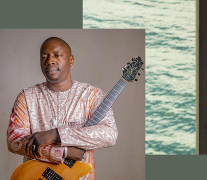 Vieux Quartet Toure a Malian singer in traditional wear holding his guitar.