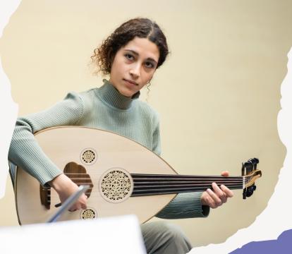 Woman in a green sweater plays an oud, displaying focus and calm. The image border is abstract with torn paper-like patterns in beige, pink, and blue.