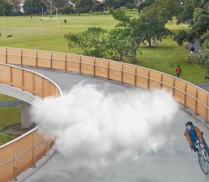 A cloud moving with a man as he cycles on a bridge.