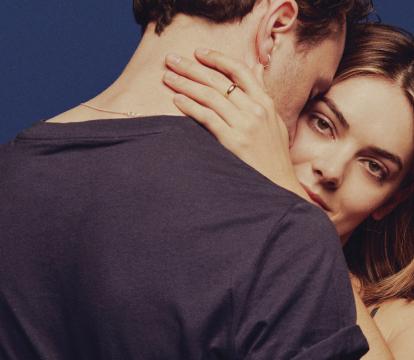 A man leaning this head on a woman's forehead and holding each other.
