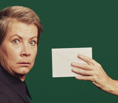 A blonde woman looking shocked after seeing a letter.