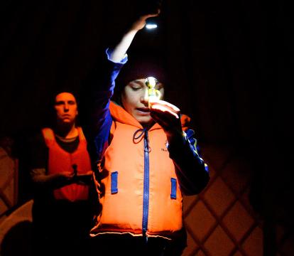 A person wearing a lifejacket and holding a torch.