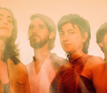 Two men and two women pose, washed in orange light.