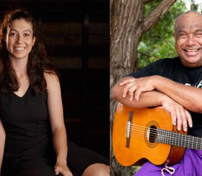 A woman with long brown hair in a black dress next to a man smiling holding a guitar.