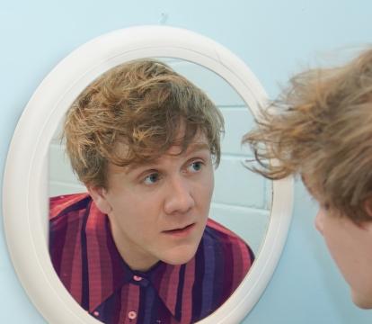 Josh Thomas staring into a mirror