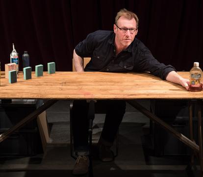 A man displays items on a tabletop.