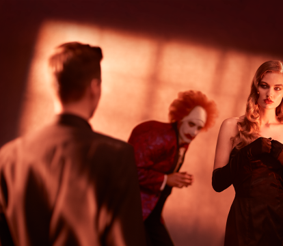 A clown in a suit and a woman in a black dress.