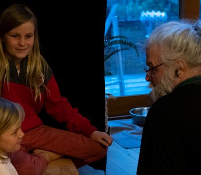 Two young girls sat down with an older man with white long hair and glasses.